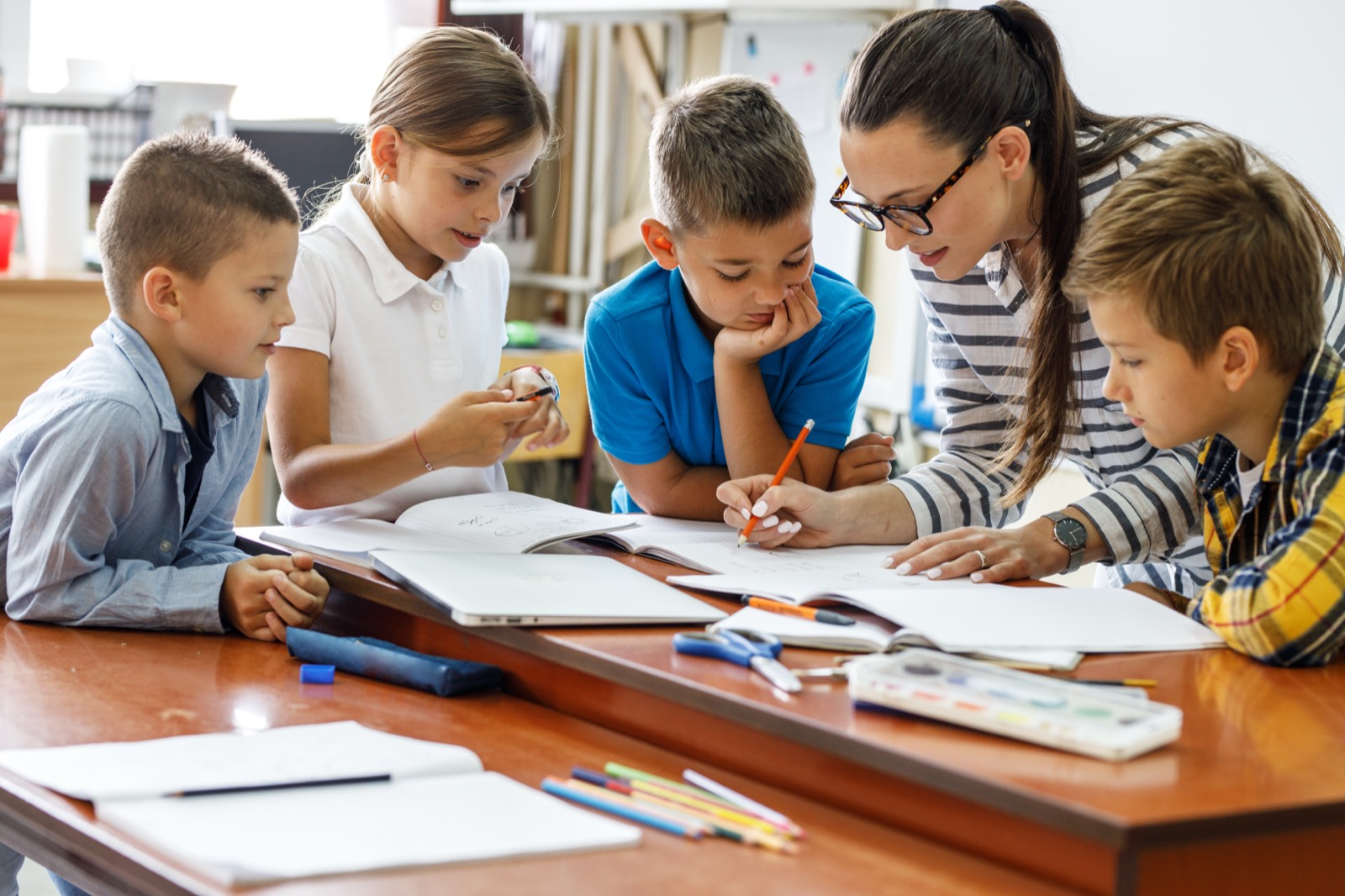 A tutor helping a small group of children with their schoolwork